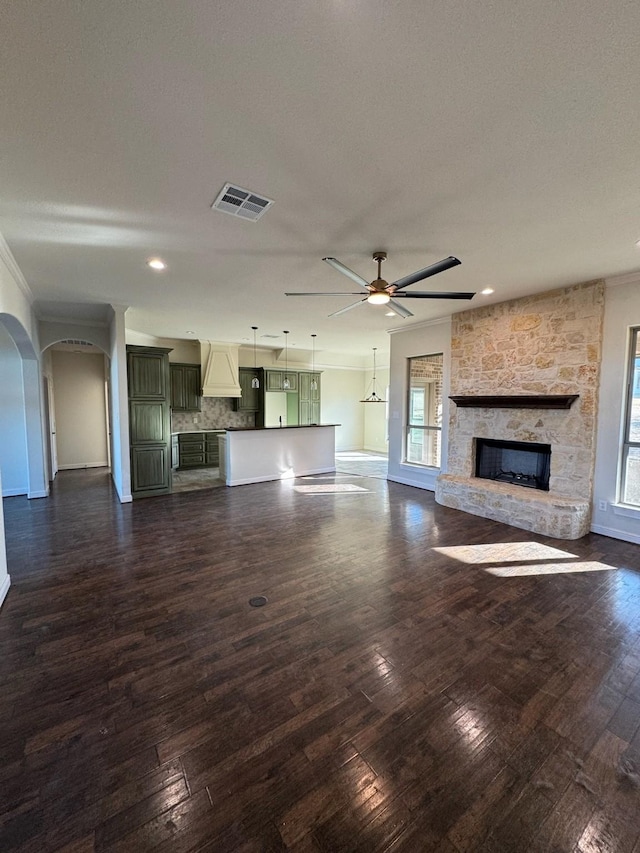 unfurnished living room featuring ceiling fan, plenty of natural light, dark wood-type flooring, and a fireplace