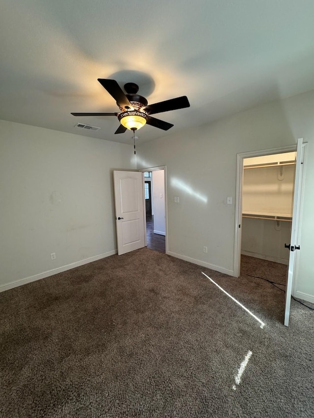 unfurnished bedroom with ceiling fan, carpet flooring, a closet, and a walk in closet