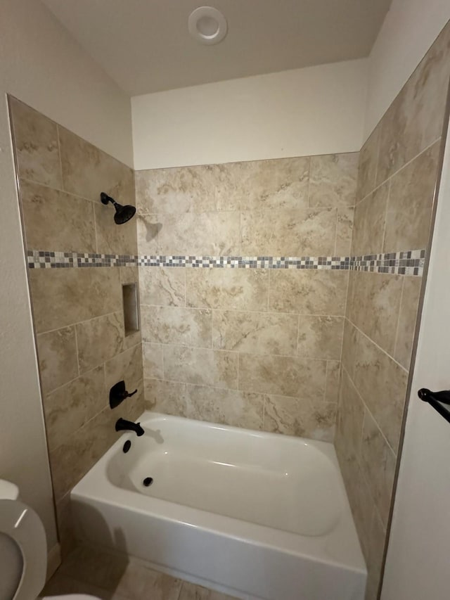 bathroom with toilet and tiled shower / bath combo