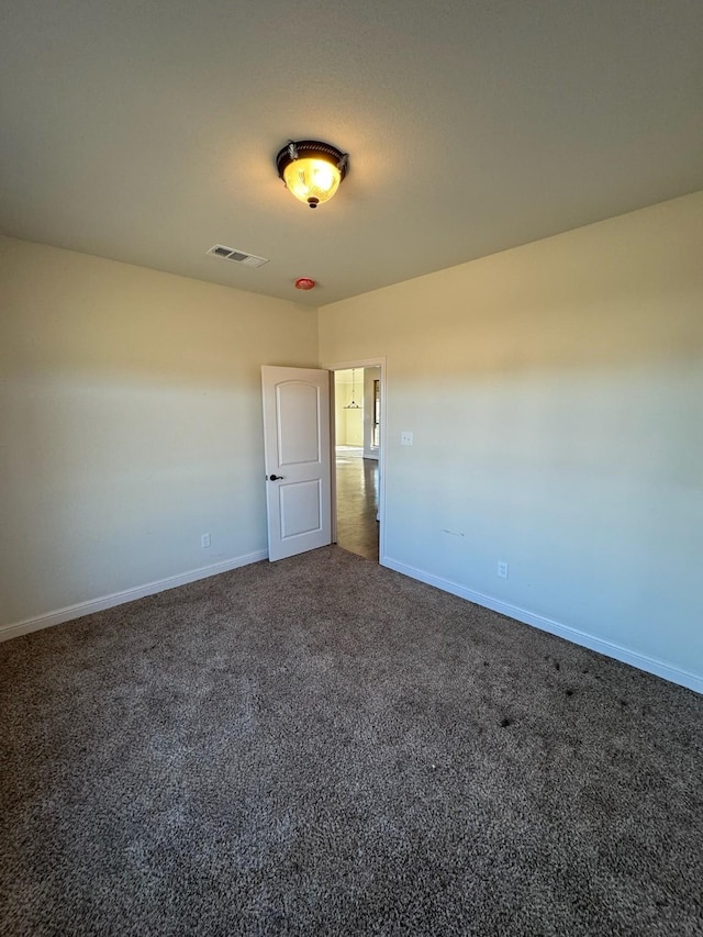 spare room featuring dark carpet