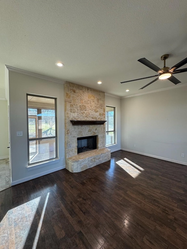 unfurnished living room with dark hardwood / wood-style flooring, crown molding, a stone fireplace, and a textured ceiling