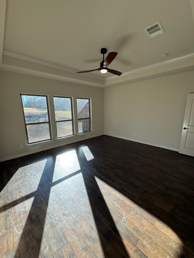 empty room featuring dark wood-type flooring, ceiling fan, and a raised ceiling