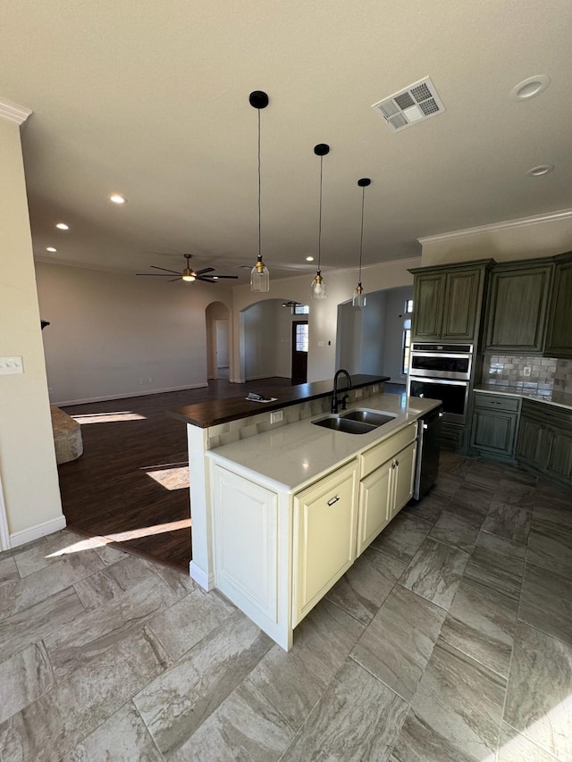 kitchen featuring a large island, sink, dark brown cabinets, tasteful backsplash, and cream cabinets