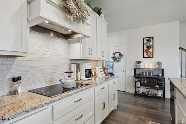 kitchen with black electric stovetop, light stone countertops, custom range hood, and white cabinets