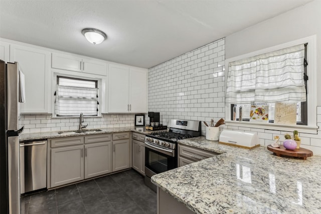 kitchen with light stone countertops, tasteful backsplash, stainless steel appliances, and a sink