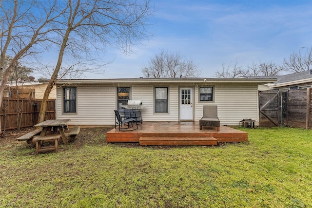 back of property featuring a gate, a fenced backyard, a yard, and a wooden deck