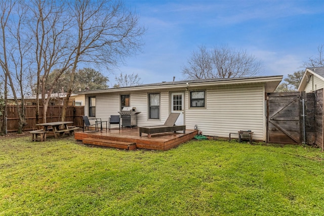 back of property with a gate, a fenced backyard, a yard, and a wooden deck