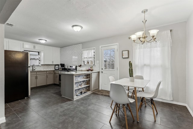 kitchen with stainless steel appliances, visible vents, white cabinets, hanging light fixtures, and decorative backsplash