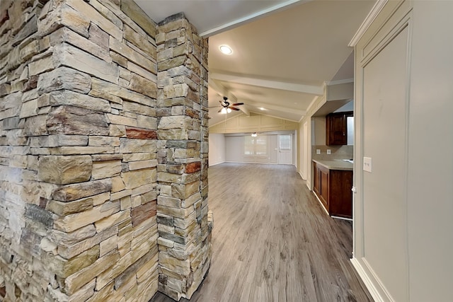 hall with lofted ceiling, ornamental molding, and light wood-type flooring