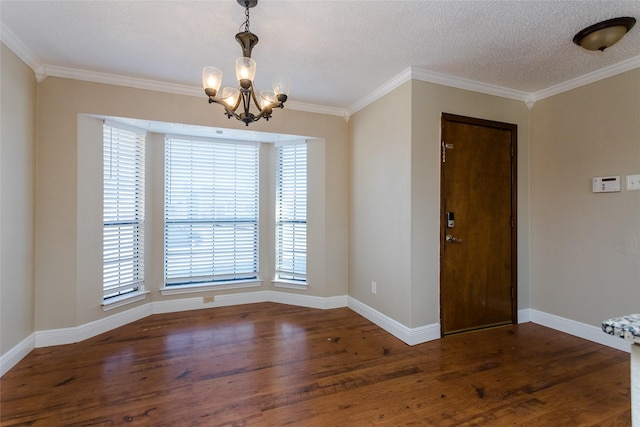 empty room featuring ornamental molding, dark hardwood / wood-style flooring, a textured ceiling, and a notable chandelier