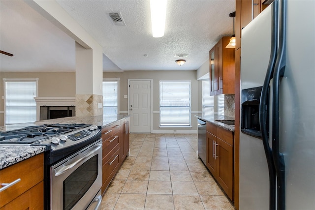 kitchen featuring decorative light fixtures, light tile patterned floors, stainless steel appliances, light stone countertops, and decorative backsplash