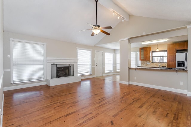 unfurnished living room with hardwood / wood-style floors, a wealth of natural light, a brick fireplace, and ceiling fan