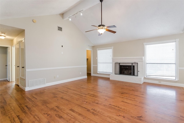 unfurnished living room featuring wood-type flooring, high vaulted ceiling, beamed ceiling, ceiling fan, and a fireplace