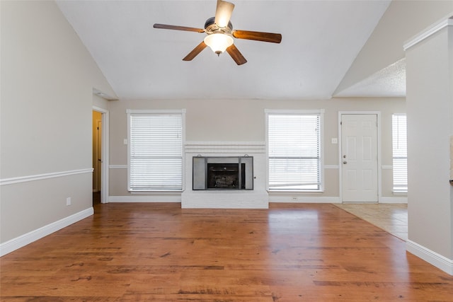 unfurnished living room featuring hardwood / wood-style flooring, lofted ceiling, a wealth of natural light, and a fireplace