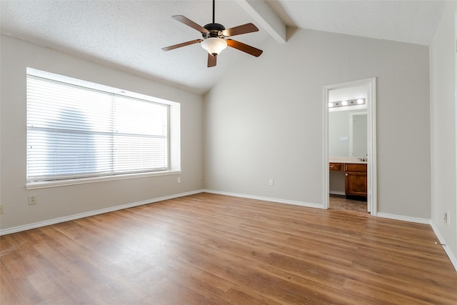 unfurnished room featuring a textured ceiling, wood-type flooring, lofted ceiling with beams, and ceiling fan