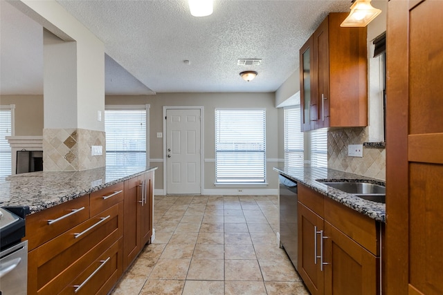 kitchen featuring light tile patterned flooring, tasteful backsplash, stainless steel appliances, light stone countertops, and a textured ceiling