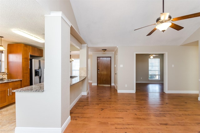 foyer featuring plenty of natural light, light hardwood / wood-style floors, vaulted ceiling, and a textured ceiling