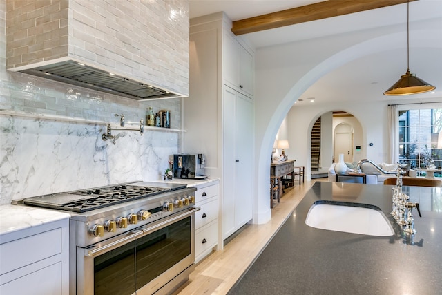 kitchen featuring white cabinetry, light stone countertops, custom range hood, and range with two ovens