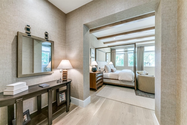 bedroom with beam ceiling and light wood-type flooring