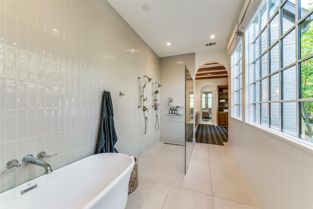 bathroom featuring plus walk in shower, tile walls, and tile patterned floors