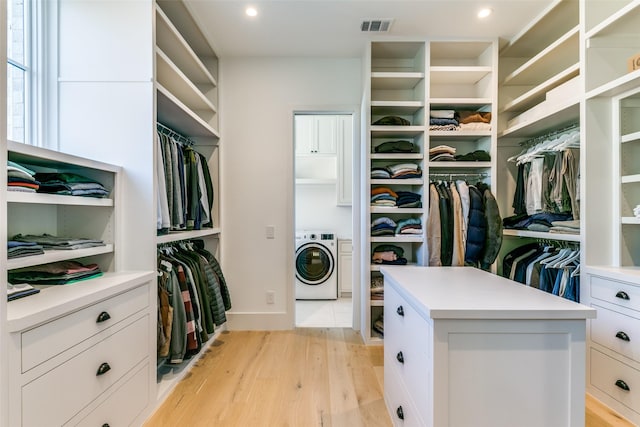 walk in closet with washer / dryer and light wood-type flooring