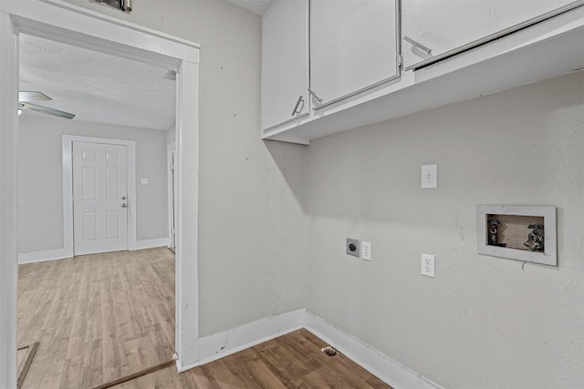 laundry room with electric dryer hookup, hookup for a washing machine, cabinets, light hardwood / wood-style floors, and a textured ceiling