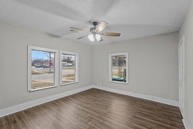 spare room featuring ceiling fan, dark wood-type flooring, and a textured ceiling