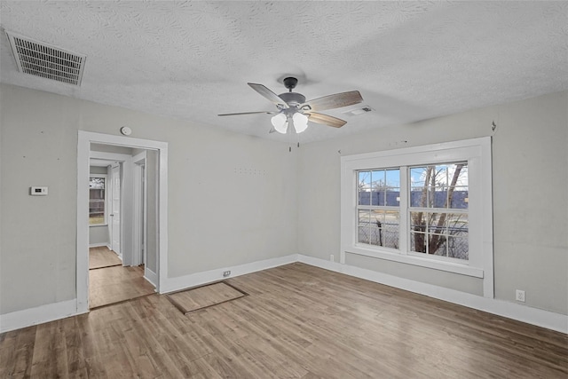 empty room featuring ceiling fan, wood-type flooring, and a textured ceiling