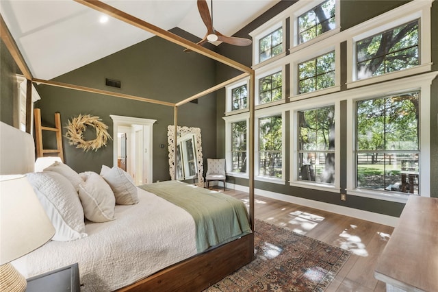 bedroom with multiple windows, wood-type flooring, and high vaulted ceiling