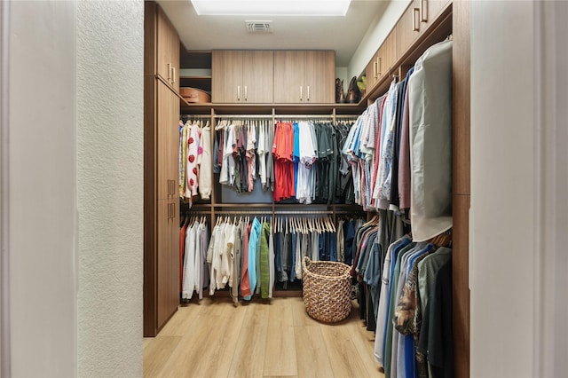 walk in closet with light hardwood / wood-style flooring