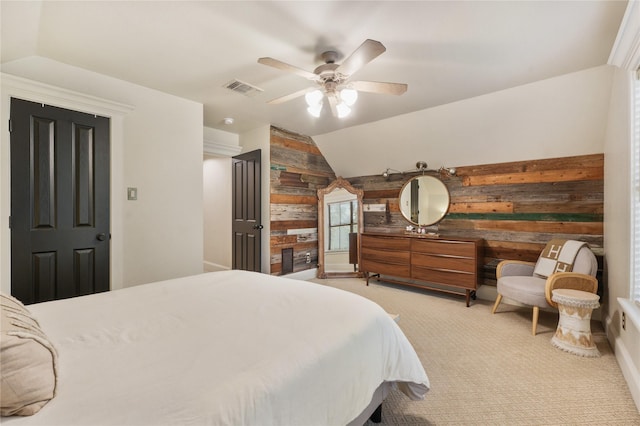 carpeted bedroom with vaulted ceiling, ceiling fan, and wooden walls