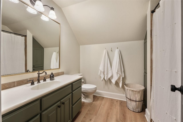 bathroom with lofted ceiling, hardwood / wood-style floors, vanity, and toilet