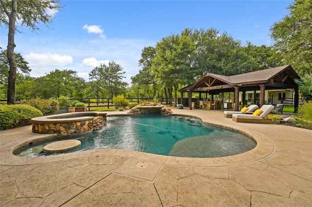 view of pool with a patio area, pool water feature, and an in ground hot tub