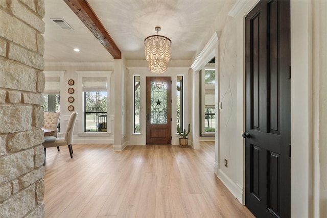 entrance foyer with an inviting chandelier, a wealth of natural light, light hardwood / wood-style flooring, and beam ceiling