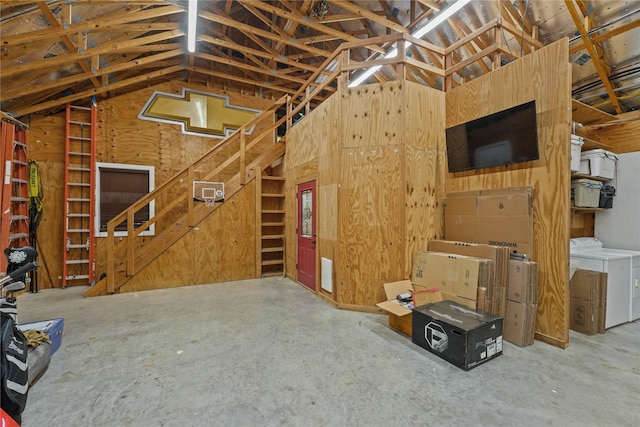 interior space featuring lofted ceiling, washing machine and clothes dryer, and wood walls