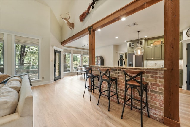 kitchen with light stone countertops, light hardwood / wood-style floors, a breakfast bar, and kitchen peninsula