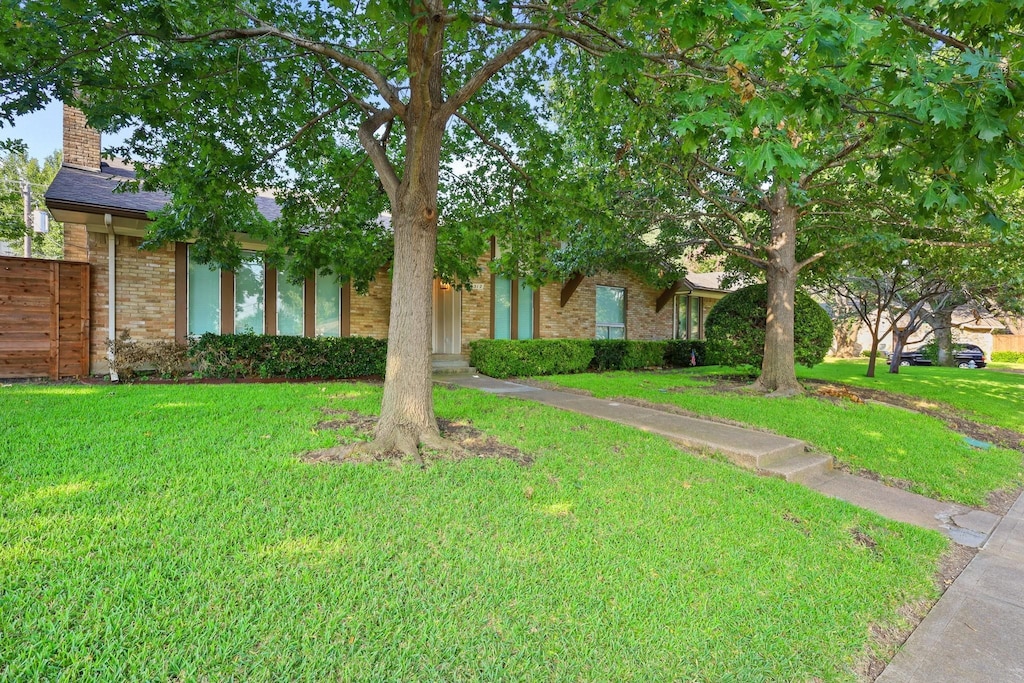 view of property hidden behind natural elements featuring a front yard