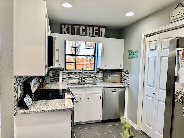 kitchen with appliances with stainless steel finishes, tasteful backsplash, sink, white cabinets, and light stone countertops