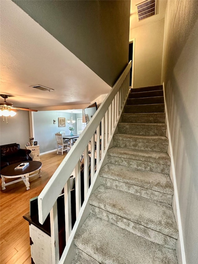 stairs with wood-type flooring and ceiling fan