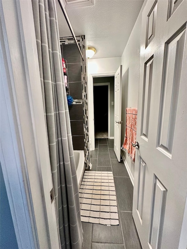 corridor with dark tile patterned flooring and a textured ceiling