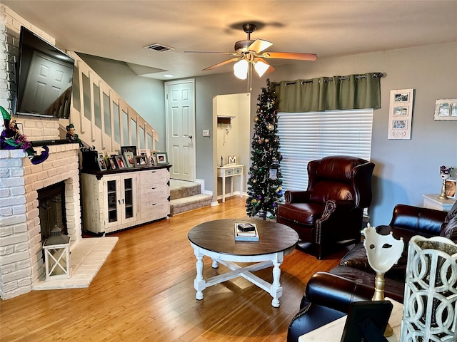 living room with a fireplace, wood-type flooring, and ceiling fan