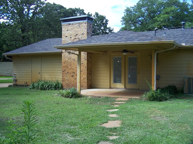 entrance to property featuring a lawn, central AC, a chimney, and a shingled roof