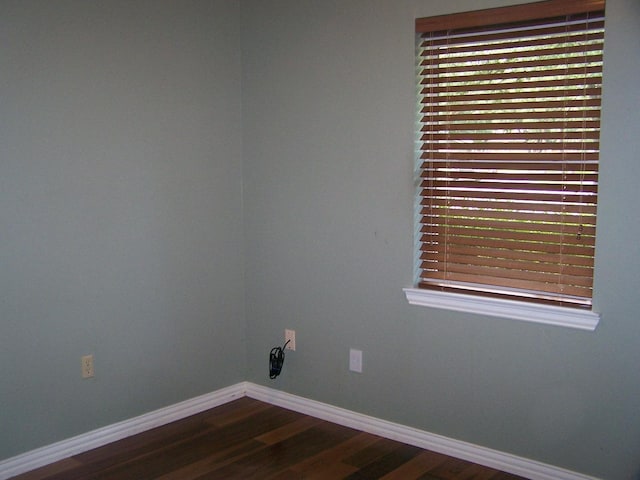 spare room featuring baseboards and wood finished floors