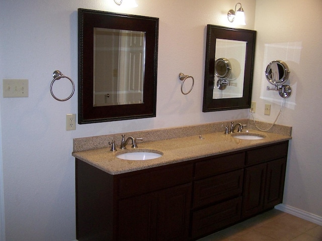 bathroom with tile patterned flooring, double vanity, baseboards, and a sink