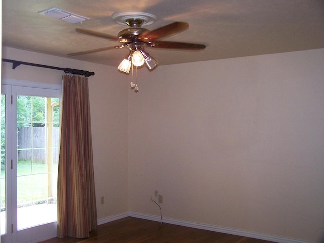 spare room featuring a ceiling fan, baseboards, visible vents, and dark wood-style flooring