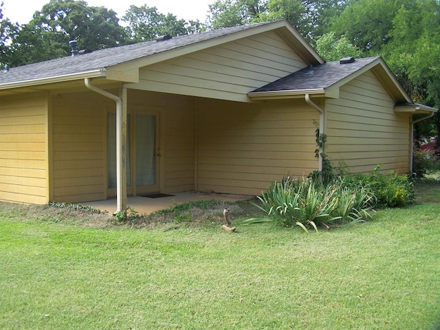 back of house with a yard, a patio area, and a shingled roof