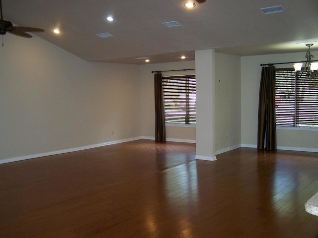 spare room featuring visible vents, dark wood-type flooring, baseboards, recessed lighting, and ceiling fan with notable chandelier