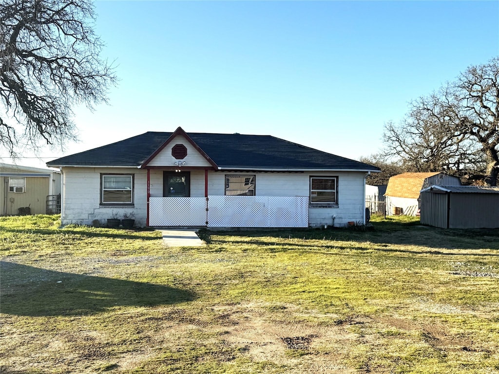 single story home featuring a storage shed and a front lawn