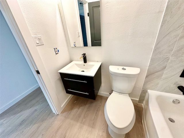 bathroom with hardwood / wood-style flooring, vanity, a bath, and toilet