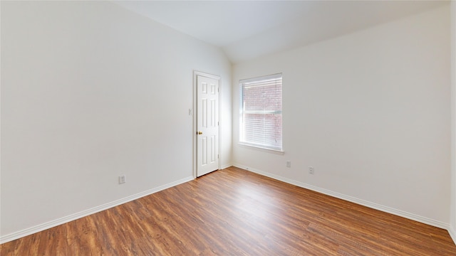 unfurnished room with hardwood / wood-style flooring and vaulted ceiling